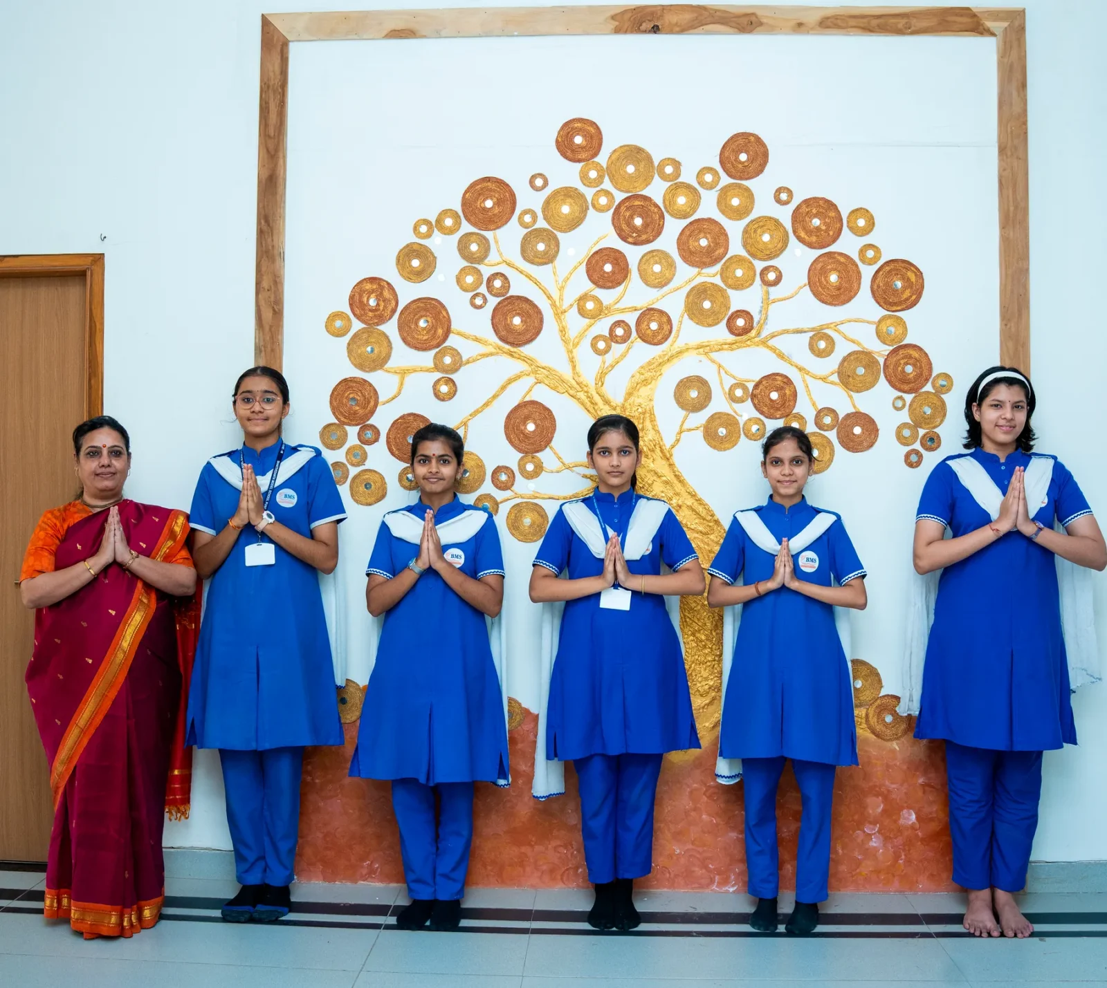 Senior students in school uniform standing with their teacher before the school assembly