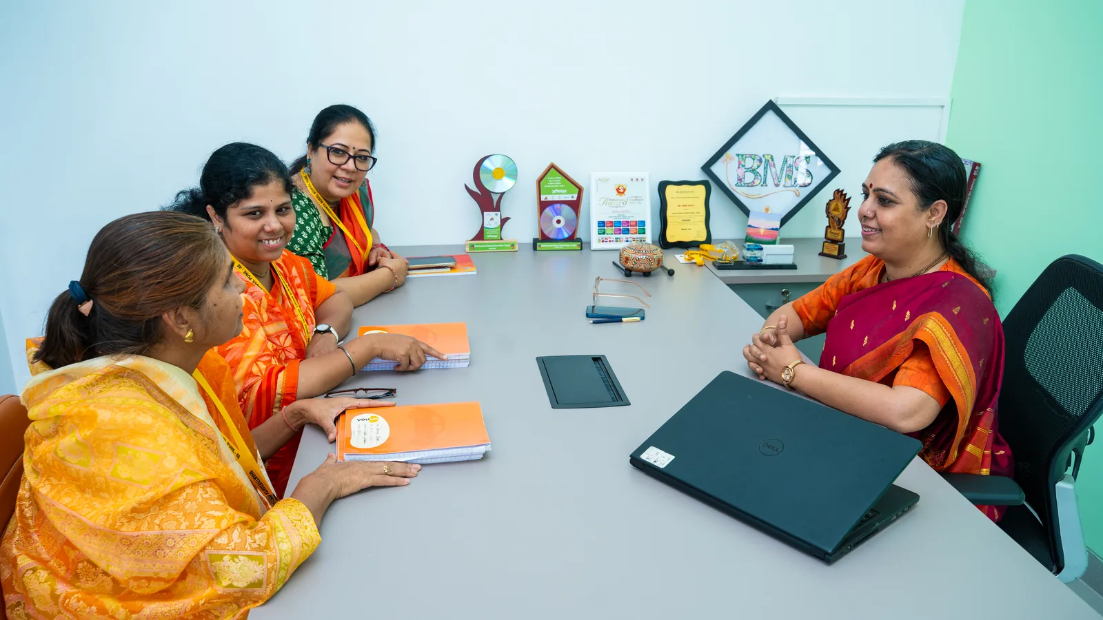 Teachers around a table with curriculum files, in discussion with the principal