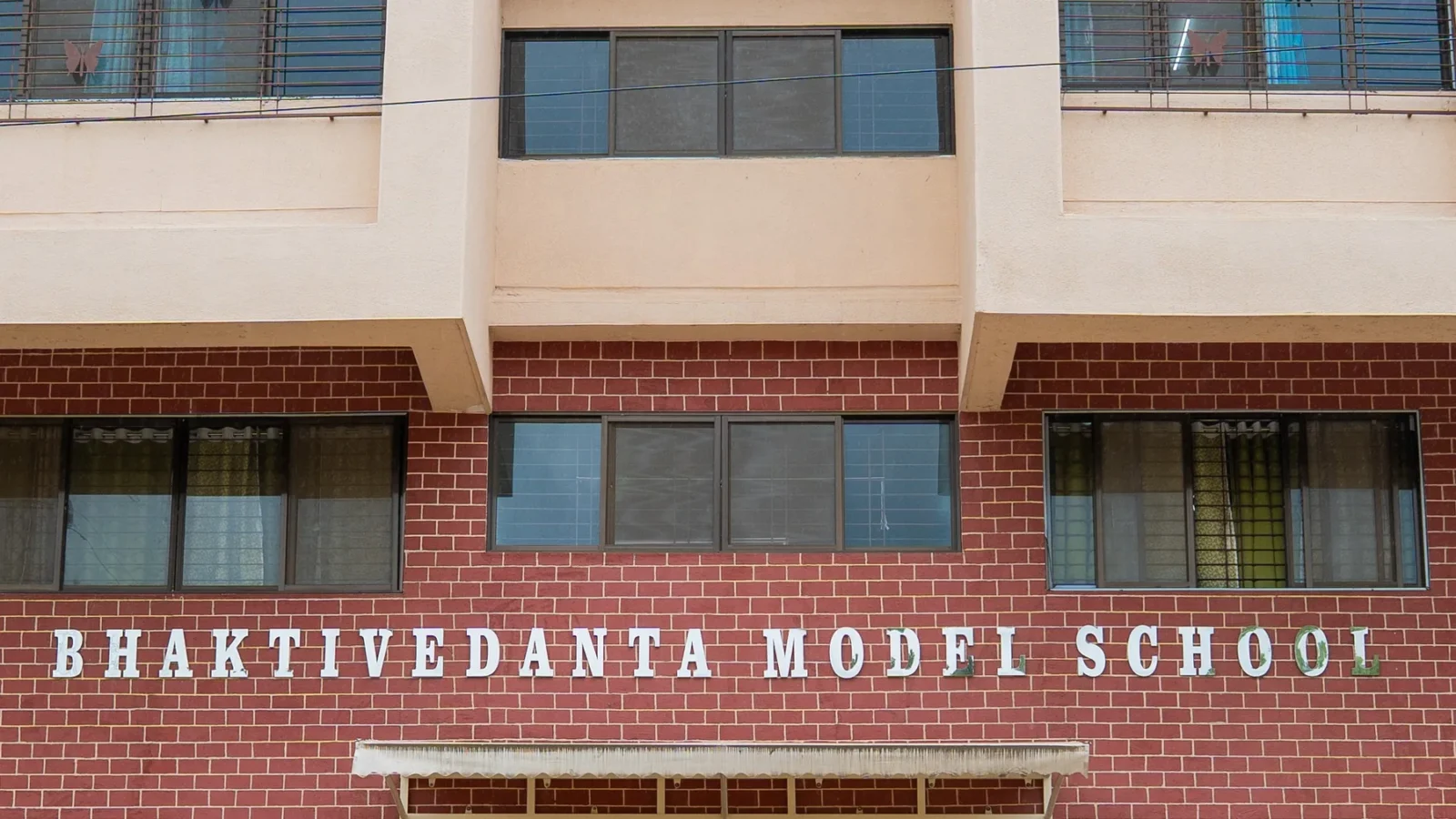 The name Bhaktivedanta Model School lettered across the brick frontage of the building