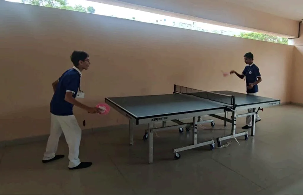 Two students playing table tennis in the indoor hall