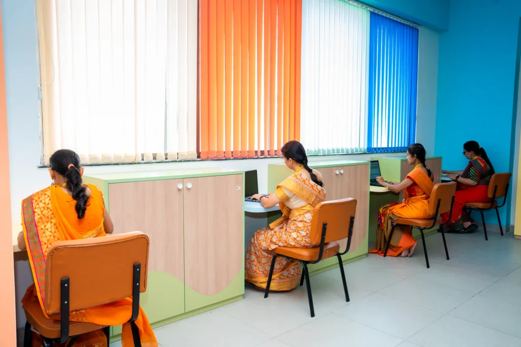 Staff at computer workstations in a room fitted with the school's coloured window blinds