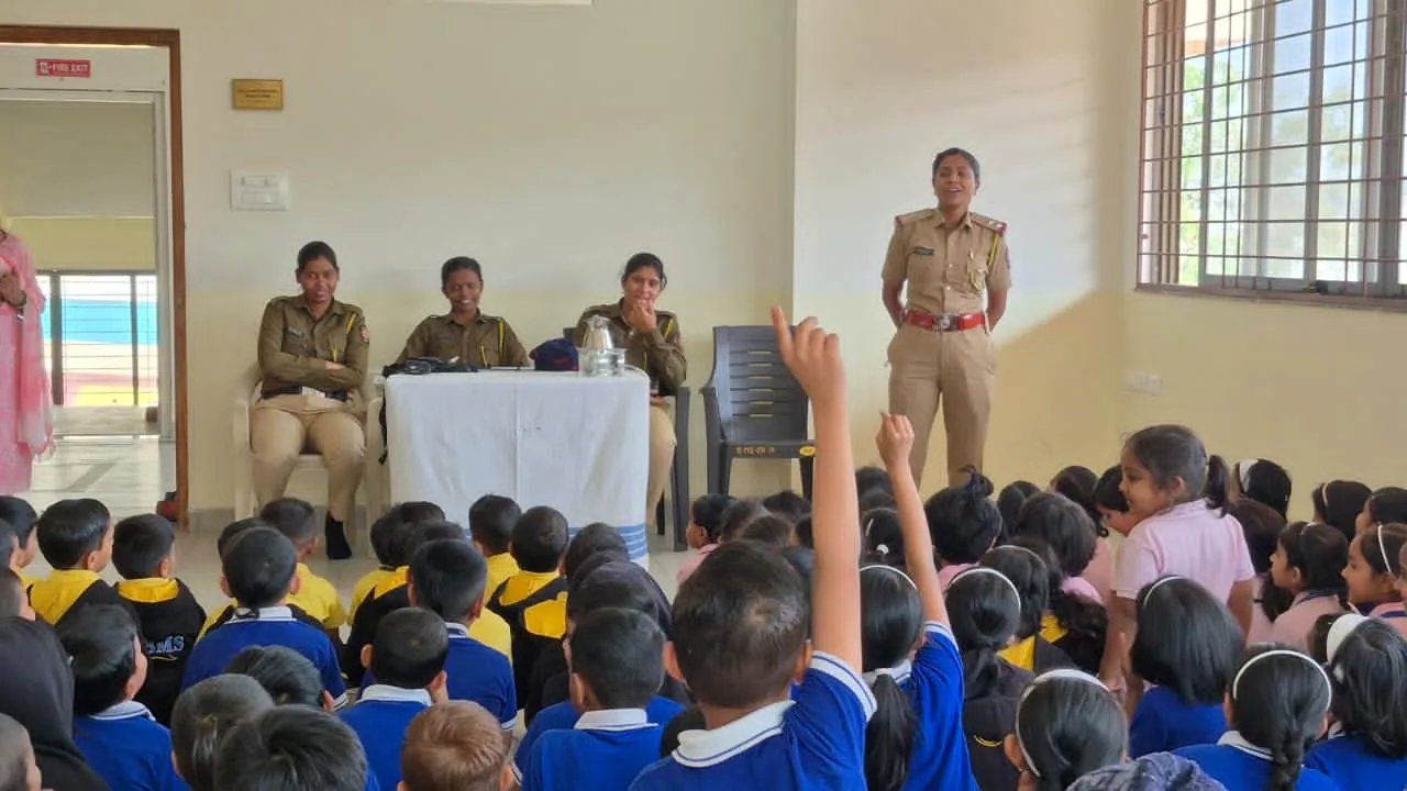 Police officers addressing the school during a safety workshop, with a child putting up a hand